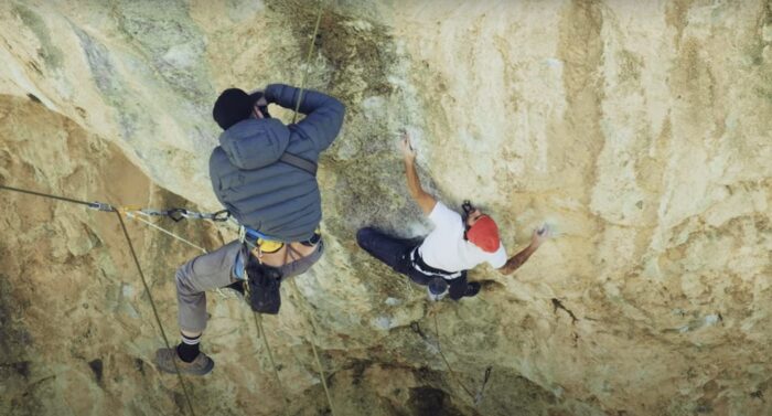 climber on steep cliff with hanging photographer